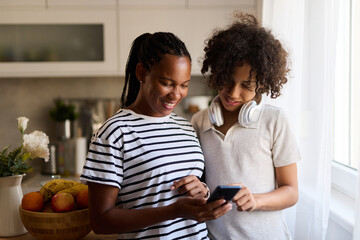 Teenage boy and his mother using smart phone at home