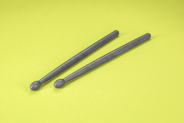 Two gray drum sticks on light green background