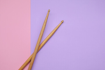 Two wooden drum sticks on color background, top view. Space for text