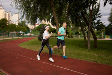 Obraz premium Senior couple running on track together outdoor at natural park