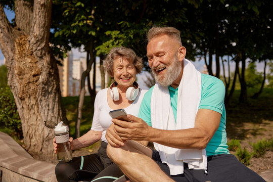 Happy overjoyed elderly man and woman couple enjoying sunny day after jogging