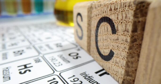 Flasks with samples of yellow liquids and the periodic table of chemical elements in laboratory