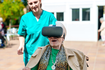 Senior lady in VR headset enjoys tech with caregiver's help in nursing home's yard.