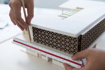 Closeup of professional architect hand measuring house model by using ruler and architectural...