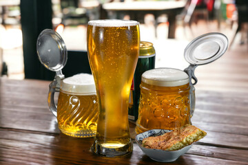 Beer in a beer glass and in beer mugs stands on a table in a cafe.