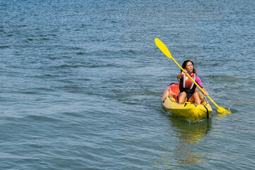young caucasian girl paddling a sit on top kayak in the mediterranean sea