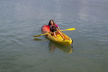 young caucasian girl sitting in a kayak in the sea looking and smiling at the camera
