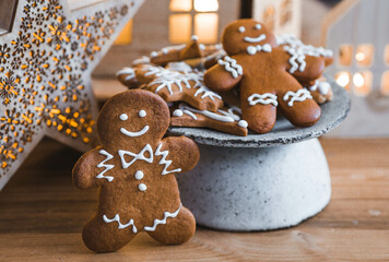 Homemade Christmas ginger cookies in powdered sugar. Delicious ginger man on the background of a bokeh of lights, Christmas houses and a Christmas tree. Freshly baked gingerbread.