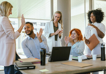 Fototapeta premium Multiethnic business colleagues smiling and celebrating success while working in the office.