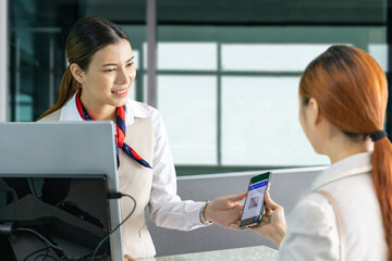 Asian passenger is showing her online check in qr code boarding pass to the airline ground crew at...