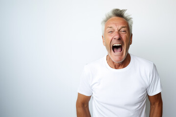 Portrait of a mature good looking man screaming, white and neutral teeshirt and background, anger