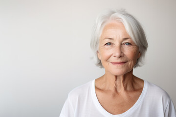 Portrait of a mature good looking woman neutral expression, white and neutral teeshirt and background - obrazy, fototapety, plakaty