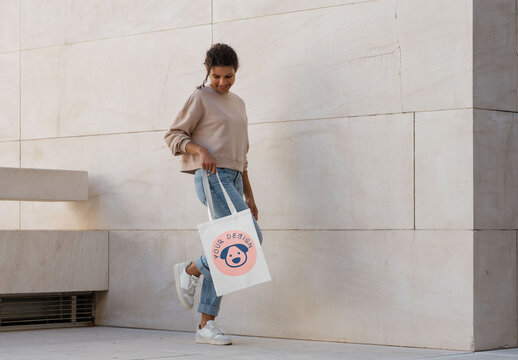 Mockup of woman holding customizable tote bag standing on one foot