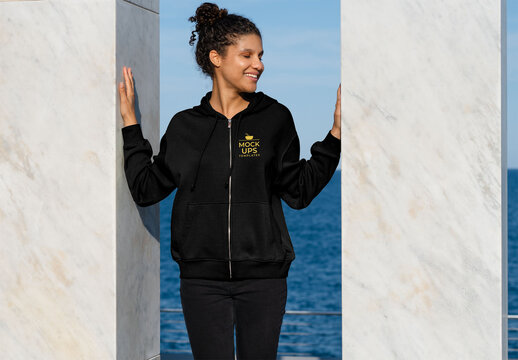 Mockup of woman wearing customizable zipper hoodie between two pillars