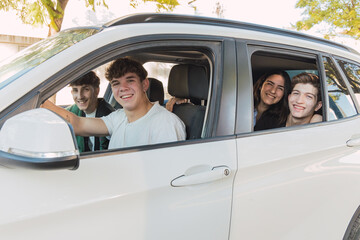Cheerful friends sitting in parked white car in daylight near building
