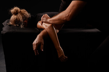 handsome male masseur giving massage to girl on black background, concept of therapeutic relaxing...