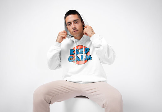 Mockup of man wearing customizable hoodie in studio putting hood up