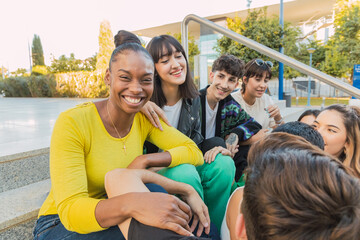Happy friends sitting on steps in sunlight