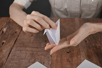 hands of an elderly woman fold origami paper. Creating an origami paper crane