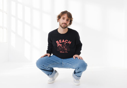 Mockup of man wearing customizable sweatshirt crouching in studio