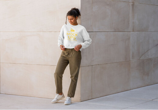 Mockup of woman wearing customizable sweatshirt by wall