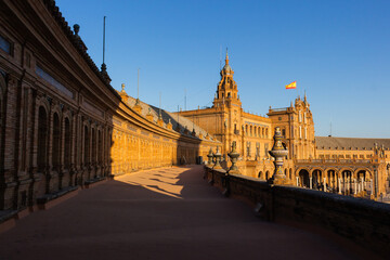 Fototapeta premium Seville, Spain, September 11, 2021: The Spanish Steps in Seville or 'Plaza de España', where the main building of the Ibero-American Exhibition of 1929 was built. Spanish flag at sunset.