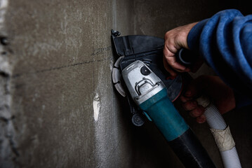 Worker holding angle grinder with two diamond discs for cutting grooves in wall. - obrazy, fototapety, plakaty