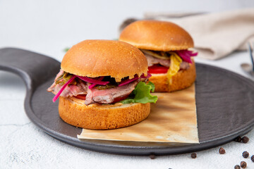 hot burgers with lettuce and vegetables on a wooden board side view