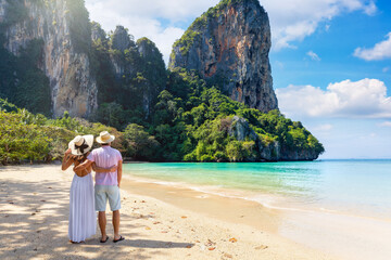 A beautiful tourist couple stands on the tropical beach of Railay at Krabi, Thailand, during their...