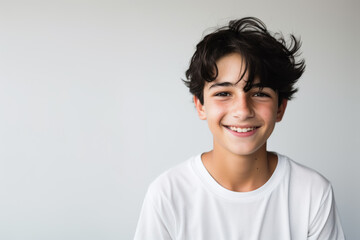 Portrait of a good looking teenager, boy, smiling, white and neutral teeshirt and background, joy