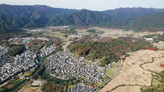 Aerial view of Chinese ancient village, Hongcun, Anhui, China. Drone fly over traditional villages in sunny autumn day with beautiful rice field and colorful forest in mountains, 4k real time footage