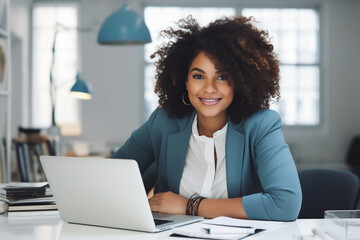 charming plump black woman of plus-size, manager, in blue business clothes sits at a desk with a laptop in a modern elegant office and smiles sweetly, the concept of diversity - obrazy, fototapety, plakaty