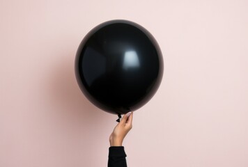 a person holds out a black balloon,