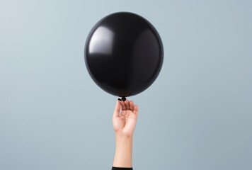 a person holds out a black balloon,
