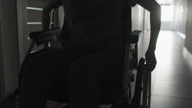 Medium close-up backlit shot of unrecognizable person on wheelchairMedium close-up backlit shot of unrecognizable person on wheelchair
