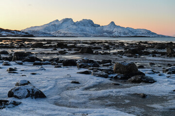 Wide angle landscape shot of the snow covered mountains and beach near Mjelle, part of the Bodo community in Arctic Norway, during the brief period of daylight in the arctic winter.