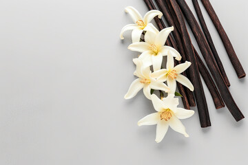 Aromatic vanilla sticks and flowers on grey background 