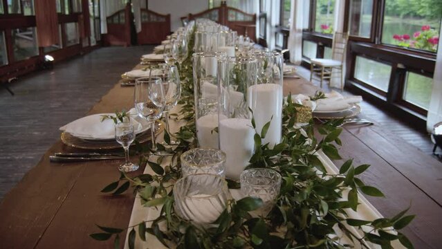 Flower arrangement on the wedding table. Decoration of the wedding table in light colors and greenery and candles. Flower arrangements for a banquet dining table.