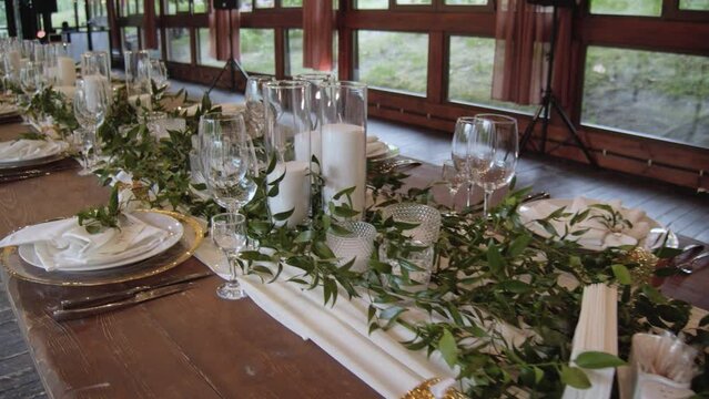 Flower arrangement on the wedding table. Decoration of the wedding table in light colors and greenery and candles. Flower arrangements for a banquet dining table.