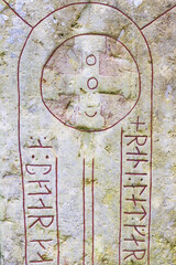 Close up at an old Runestone with runes and a cross
