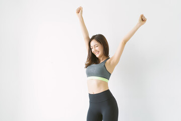Beautiful body slim confident Asian Korean in sportswear posing raise up hands with eyes closed over white backgroundover white wall background with copyspace for text.  Sport And Healthy Lifestyle