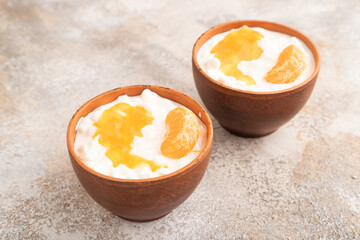 Grained cottage cheese with tangerine jam on brown concrete, side view.