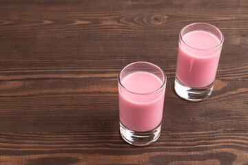 Sweet strawberry liqueur in glass on a brown wooden. side view, copy space