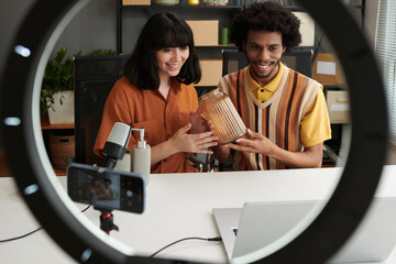 Happy young intercultural couple of shopaholics or artisans showing vase