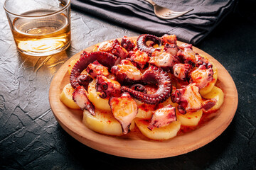 Pulpo a la gallega, Spanish octopus snack, Galician dish, shot on a black background with wine © CookShootsFood