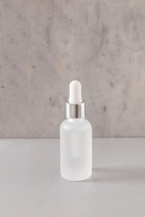 Cosmetic matte bottle with dropper for product presentation on marble wall background. Front view. Empty packaging. mockup
