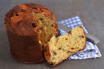 Panettone tranché avec un couteau et une serviette  en gros plan sur fond gris