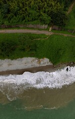 Wide aerial panoramic view Railway Station and Black Sea coast flora with calm seashore in summer. Rain clouds, storm. Tsikhisdziri Georgia. Vertical photo