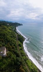 Wide aerial panoramic view scenic Black Sea coast flora with calm seashore in summer. Petra Fortress parking. Tsikhisdziri Georgia. vertical photo