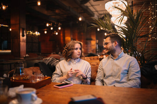 soft focus photo, a couple in love in a cafe sitting on the sofa and drinking tea